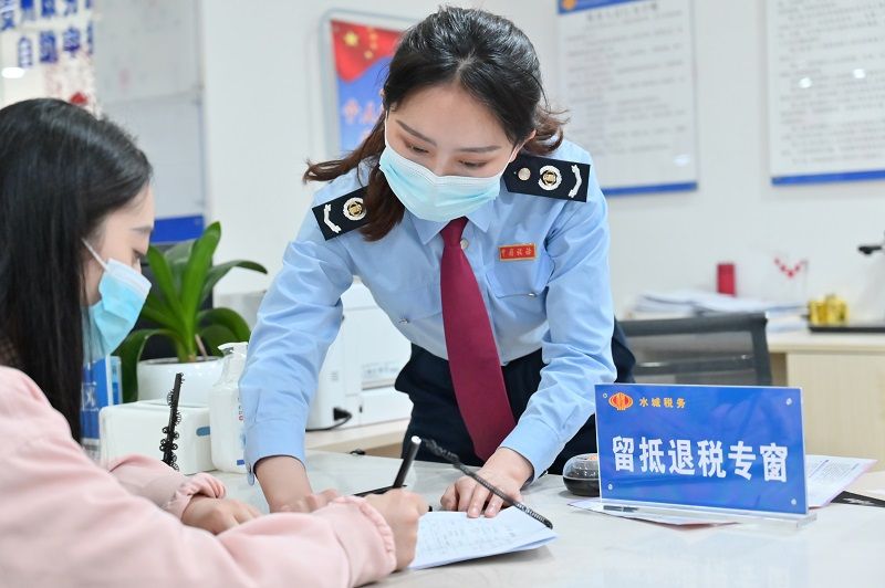 水城區(qū)稅務(wù)局窗口工作人員正在輔導(dǎo)納稅人填寫資料。（張定國(guó)攝）.jpg